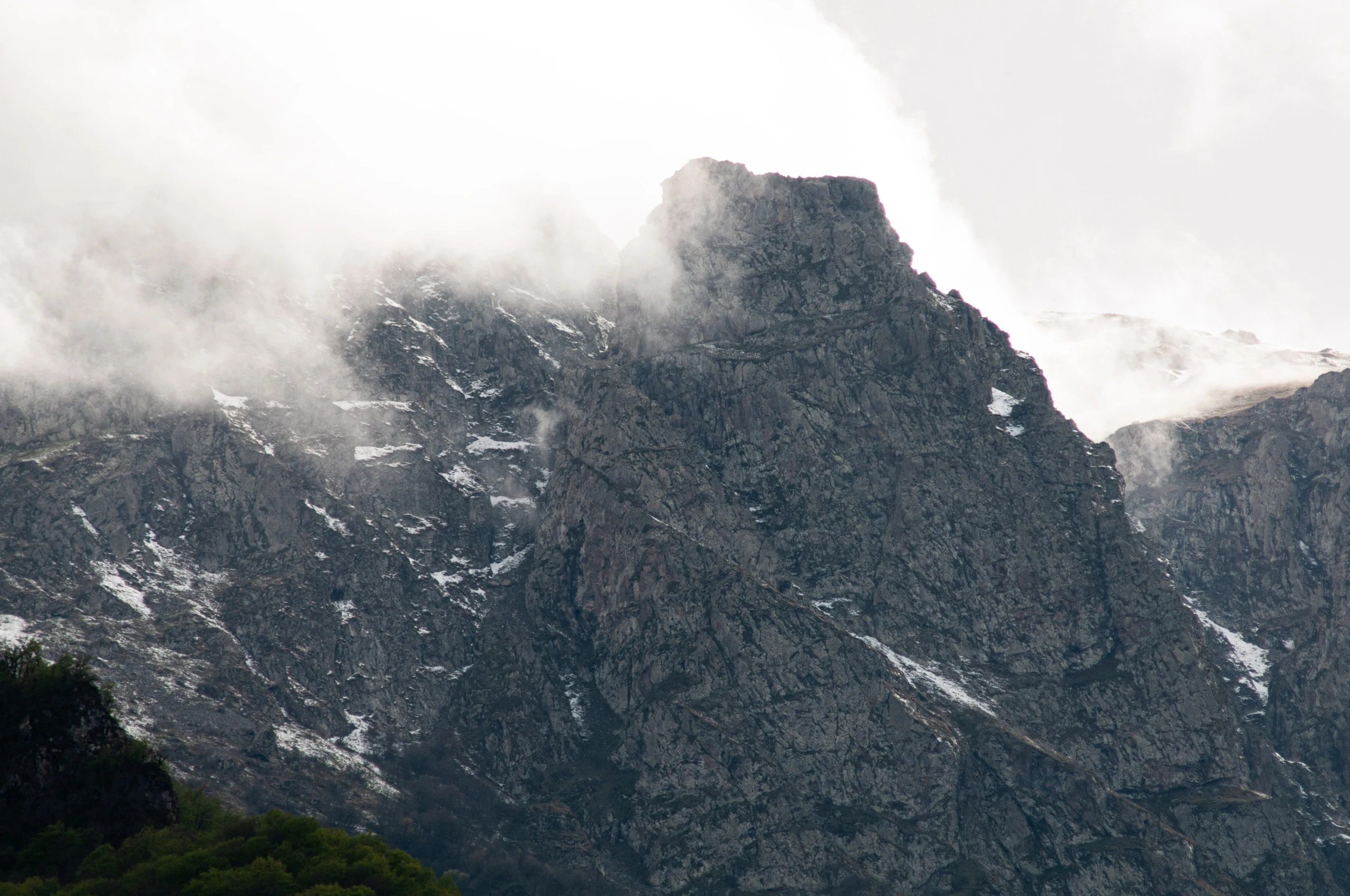 Rock face of Mount Khustup beneath drifting clouds and small patches of snow.