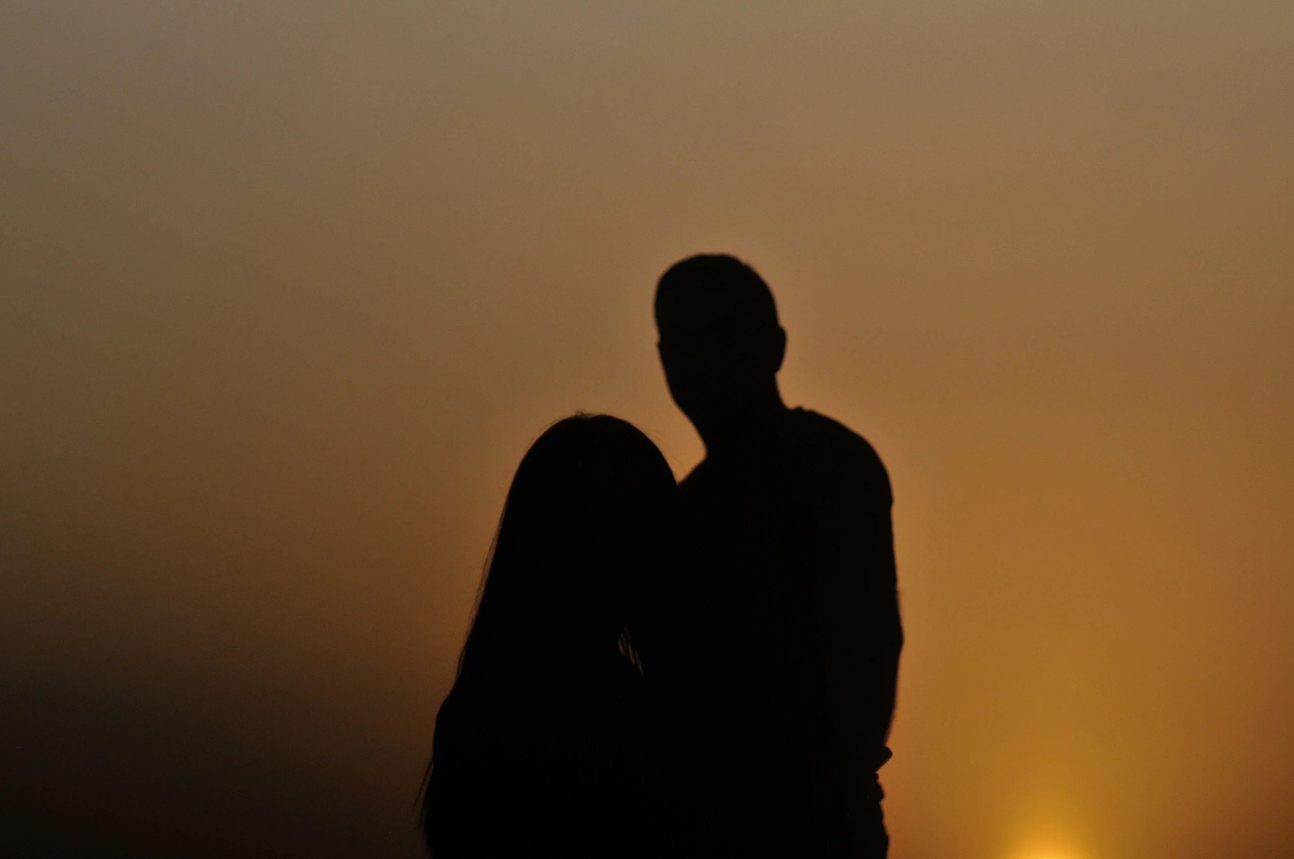 Two people silhouetted against an orange sunset at Yeritsvank.