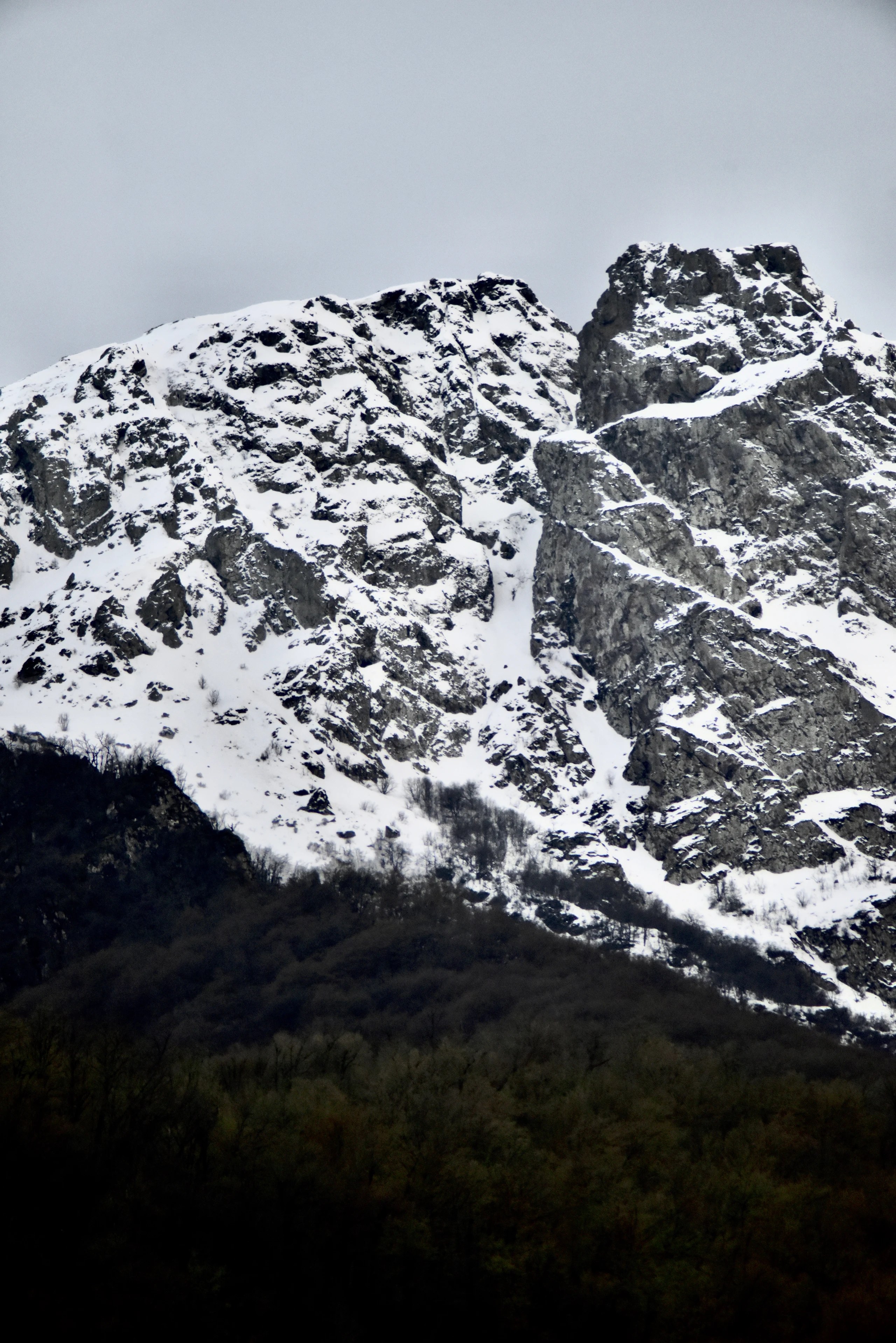 Snow-covered rock faces above a dark forest.